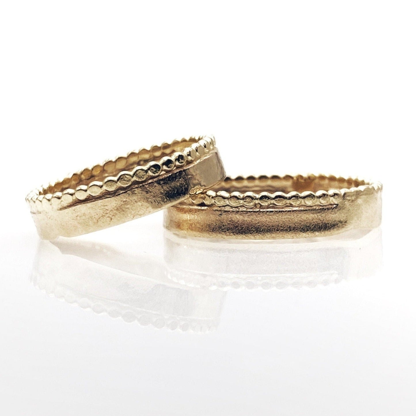 A pair of ancient style gold wedding rings with a hammered and polished finish.