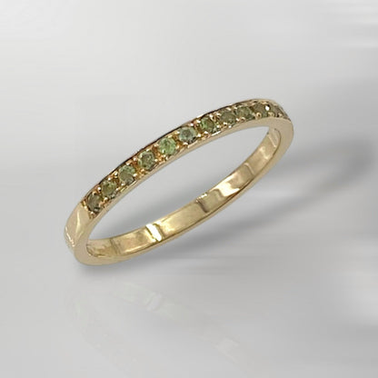 A 14K solid gold green sapphire half eternity ring with a minimalist design, featuring a single row of green sapphires on the band.