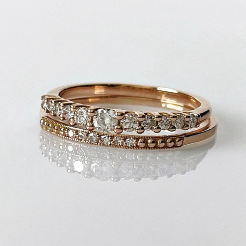 Two 14k rose gold diamond rings stacked on top of each other, with one featuring a row of natural diamonds on the top band and a pavé band below.