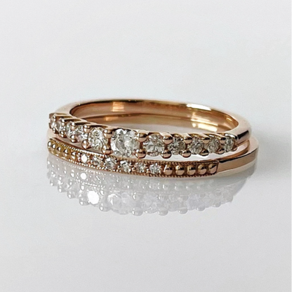 Two 14k rose gold diamond rings stacked on top of each other, with one featuring a row of natural diamonds on the top band and a pavé band below.