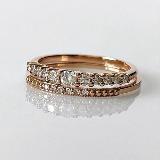Two 14k rose gold diamond rings stacked on top of each other, with one featuring a row of natural diamonds on the top band and a pavé band below.