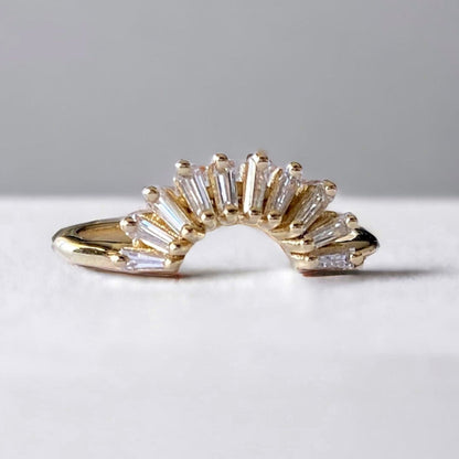 A tapered diamond gold nest ring with multiple bands of diamond accents arranged in a fan-like pattern, set against a neutral background.