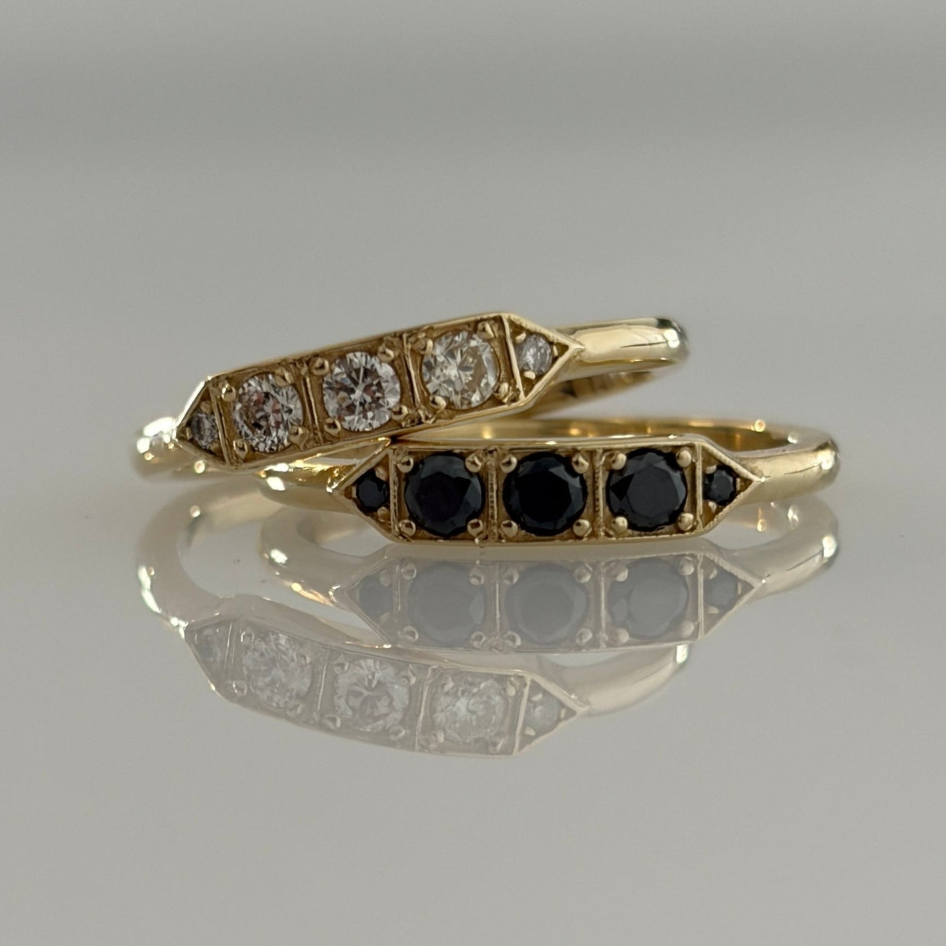 Two Art Deco style diamond rings with one featuring a yellow gold band and the other in white gold, displayed against a neutral background.