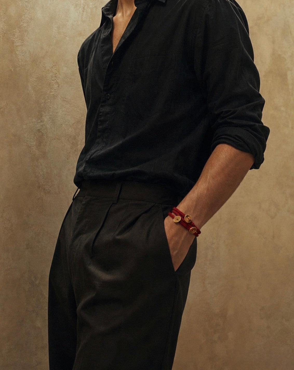 Man wearing a black shirt and pants against a beige wall