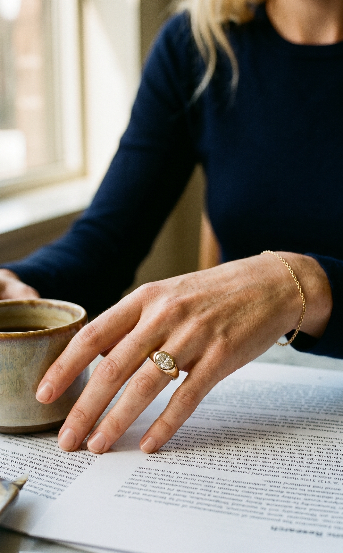 Person holding a mug with a document open on a table