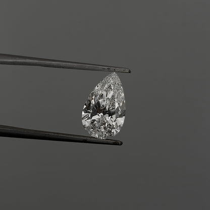 Teardrop-shaped diamond held between tweezers against a gray background