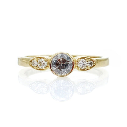 A 14k gold band ring with a central salt and pepper natural diamond and two side white natural diamonds.
