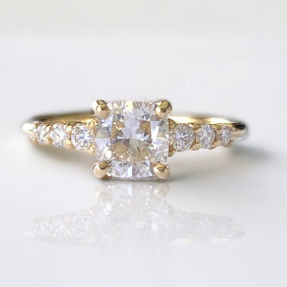 A 14k gold engagement ring with a 1.2ct lab-grown diamond centerpiece and round diamonds on the sides.