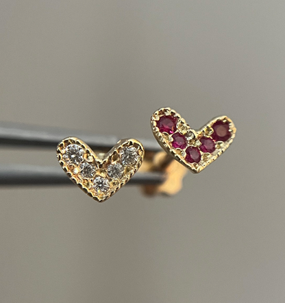 A pair of gold heart-shaped stud earrings, one with diamond accents and the other with ruby stones.