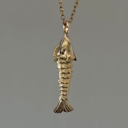 A gold pendant necklace featuring a small, detailed fish charm necklace