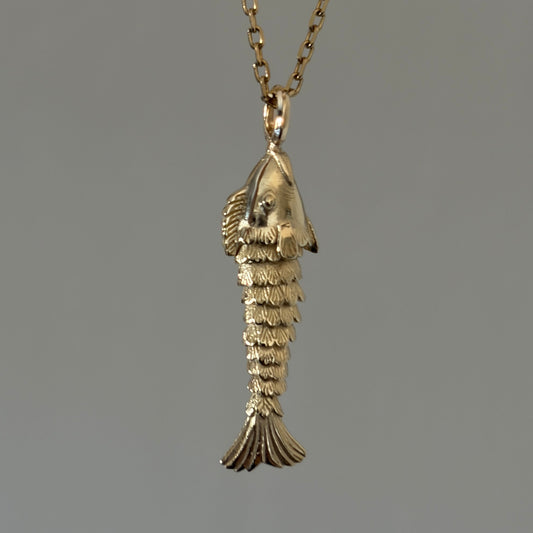 A gold pendant necklace featuring a small, detailed fish charm necklace