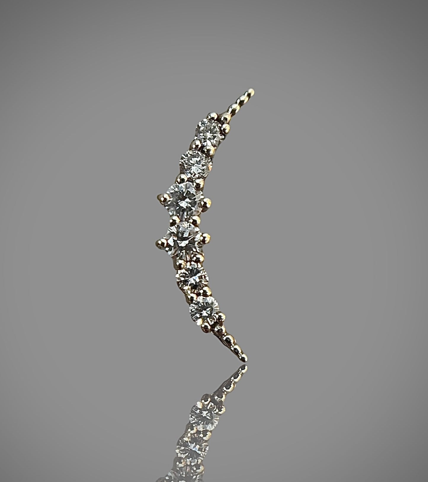 moon-shaped stud earring made of 14k solid gold with natural diamonds, against a grey background.