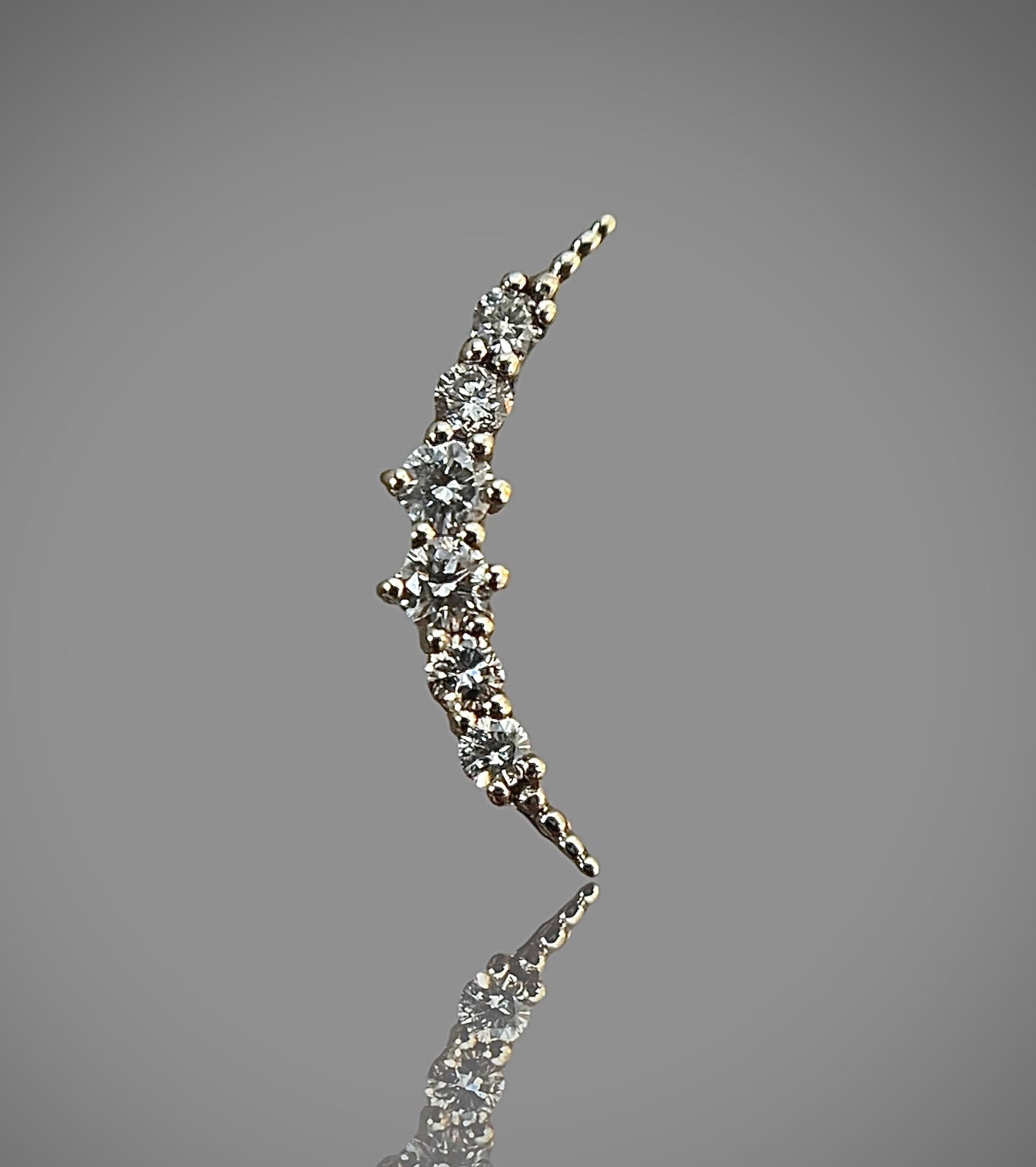 moon-shaped stud earring made of 14k solid gold with natural diamonds, against a grey background.