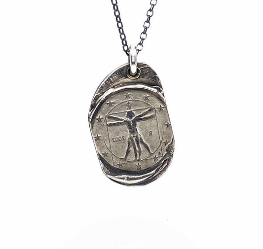 A silver necklace featuring a pendant with a design based on Leonardo Da Vinci's Vitruvian Man masterpiece, displayed against a white background.