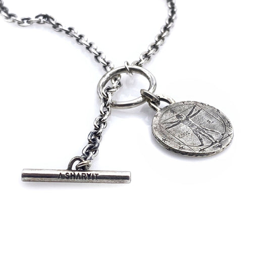 A silver necklace featuring a round coin pendant with an engraving, attached to a silver chain.