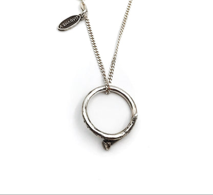 A sterling silver necklace with a handcrafted circle nail pendant, oxidized and polished for a shiny finish.