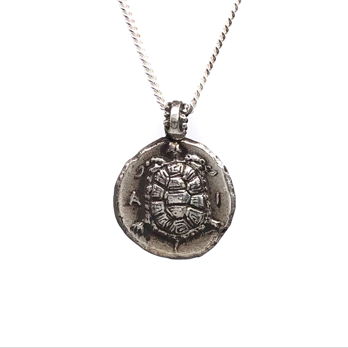 A sterling silver sea turtle coin pendant necklace on a silver chain against a white background.