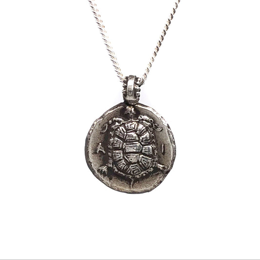 A sterling silver sea turtle coin pendant necklace on a silver chain against a white background.