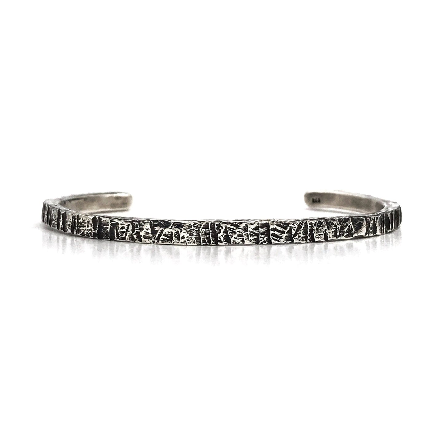 A sterling silver cuff bracelet with an oxidized and polished textured finish, giving it a realistic scratched appearance.