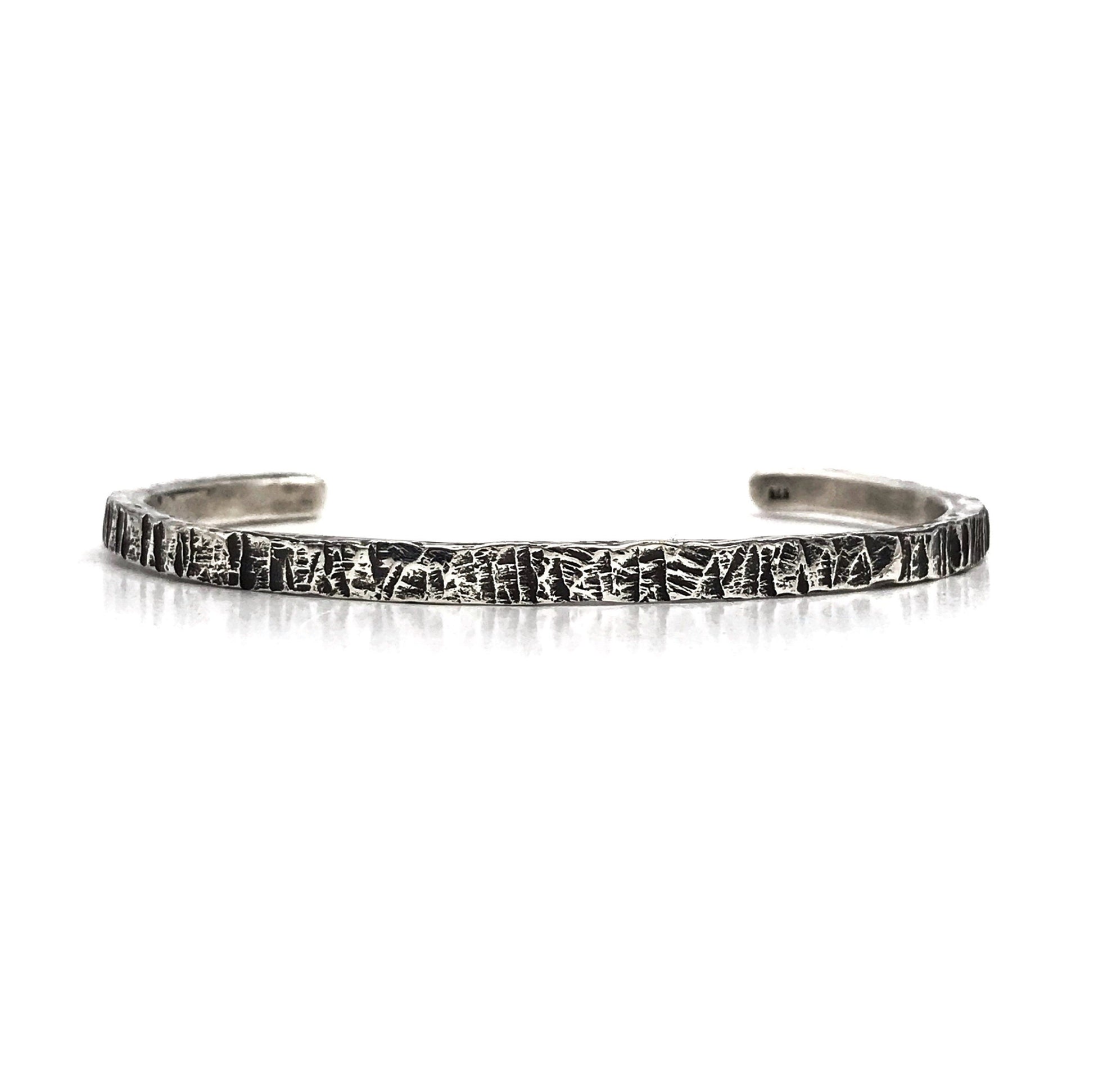 A sterling silver cuff bracelet with an oxidized and polished textured finish, giving it a realistic scratched appearance.