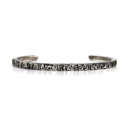 A sterling silver cuff bracelet with an oxidized and polished textured finish, giving it a realistic scratched appearance.